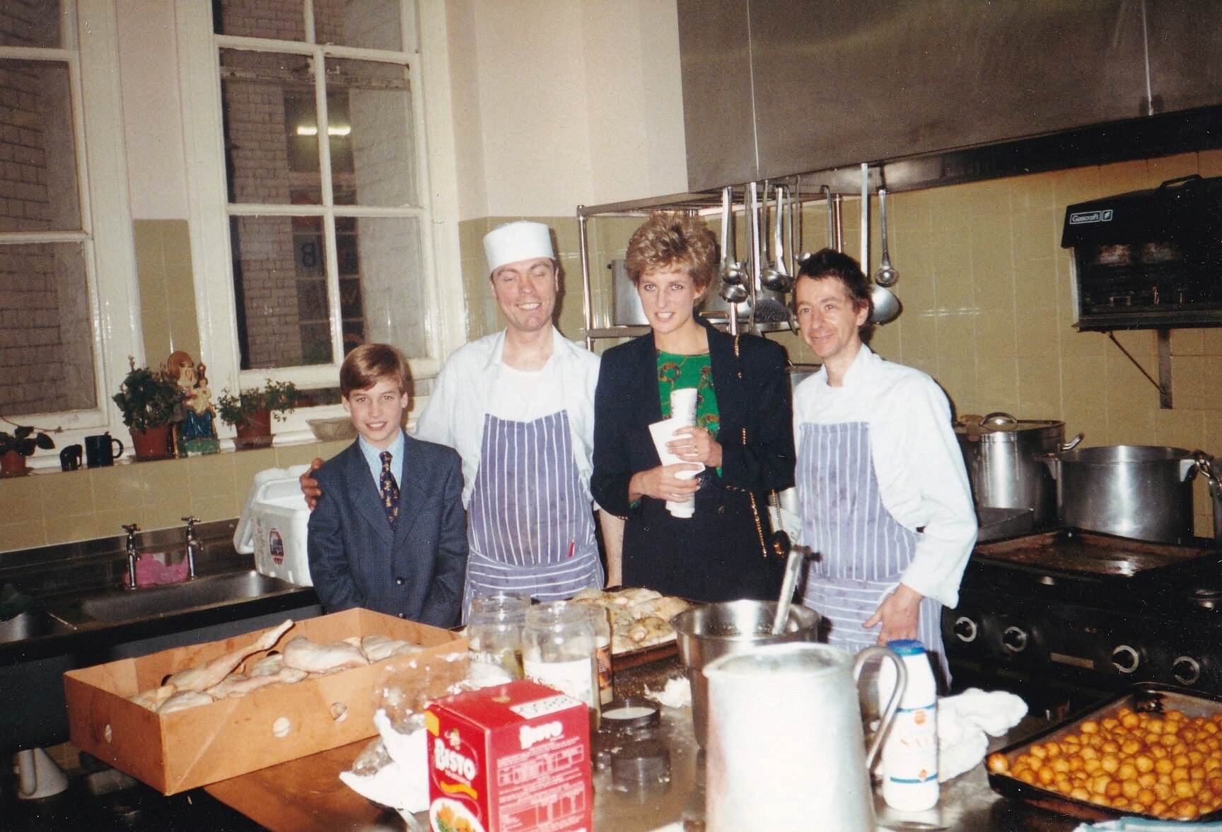 A small boy in a suit, chef with apron and woman wearing green shirt and black blazer 