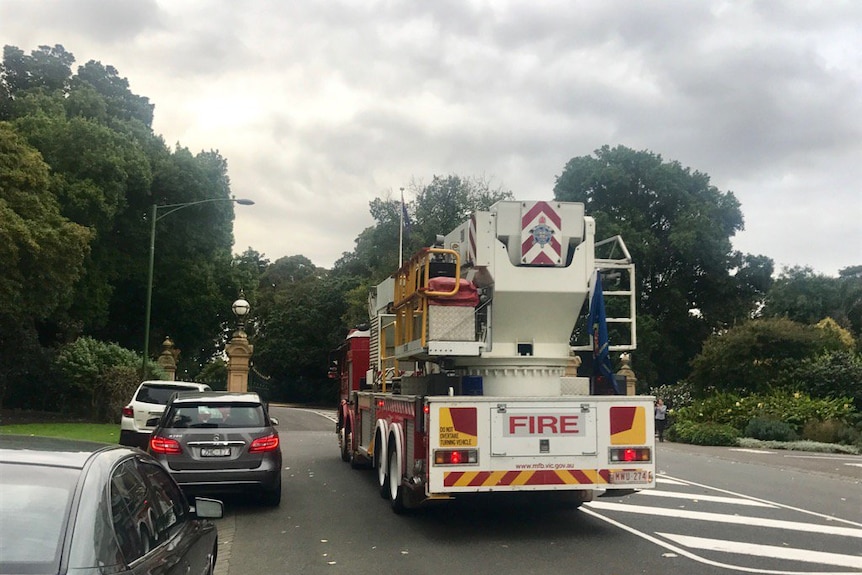 A fire truck and a car enter the gates of Government House.