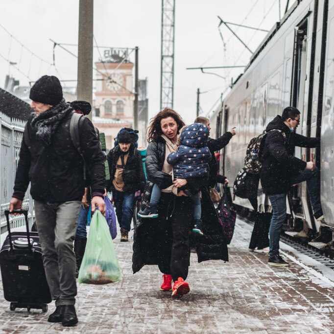 A woman walks along a platform at the Kyiv train station carrying a small child, March 1, 2022. She looks worried.