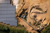 An aerial view looking down at a solar panel farm next to a sand mine with a dozer operating