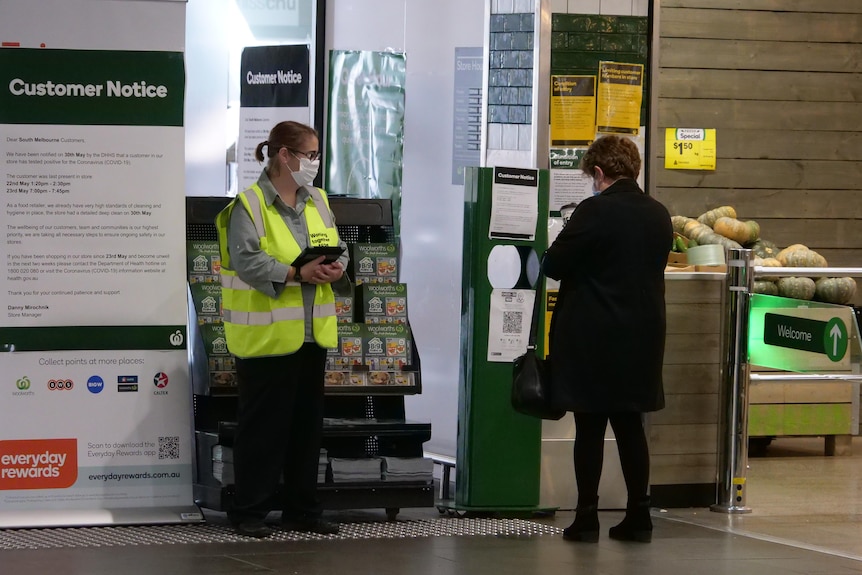A person scans a QR code before entering a shop.