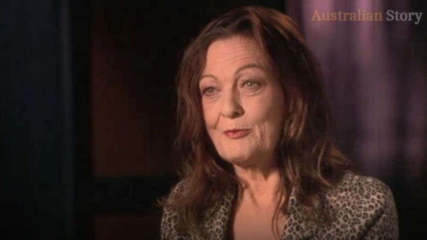 Rosslyn Dillon, a woman with brown hair and a printed top, speaks to Australian Story against a purple background.