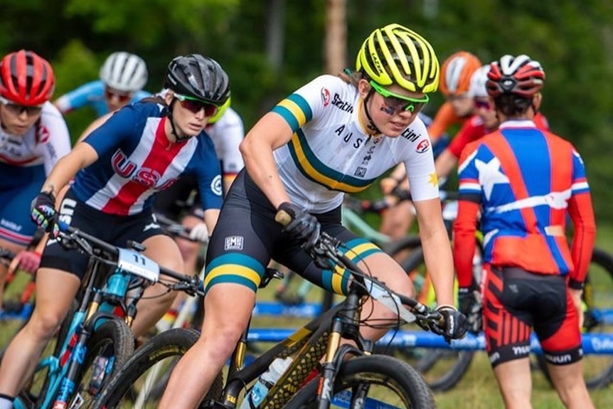 A woman races through a forest on a bike