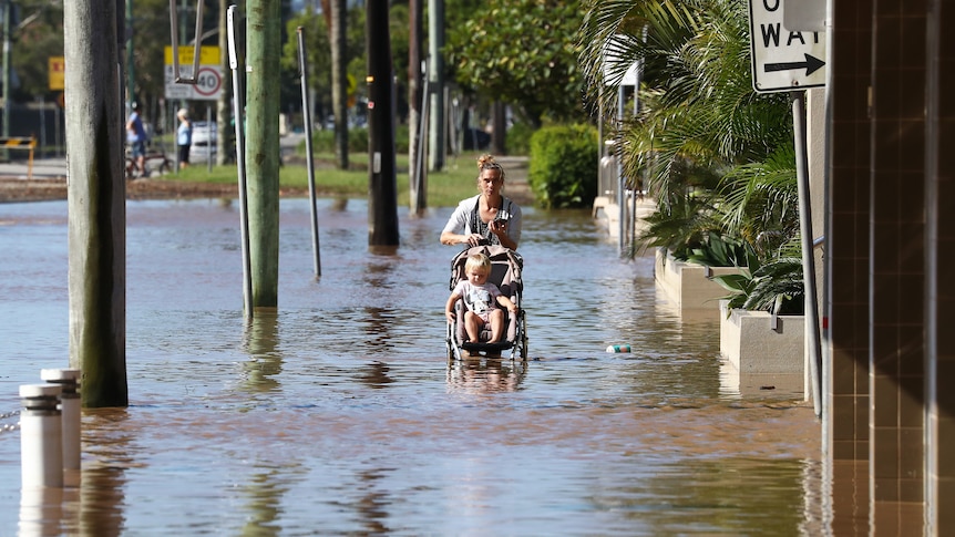 A woman with a pram walking through flood waters.