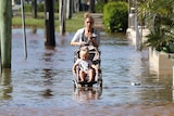 A woman with a pram walking through flood waters.