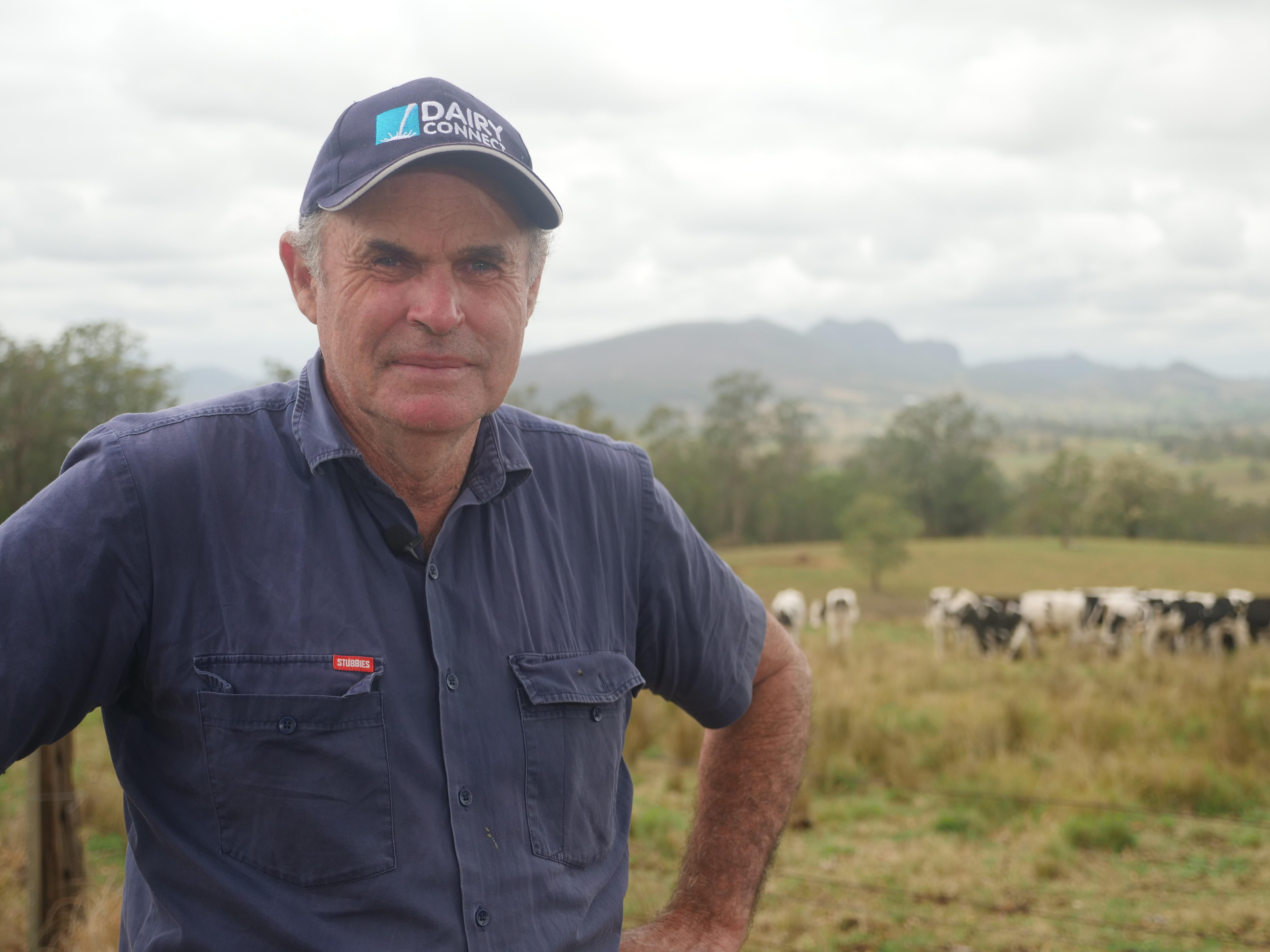Close up of a man with dairy cows in the background