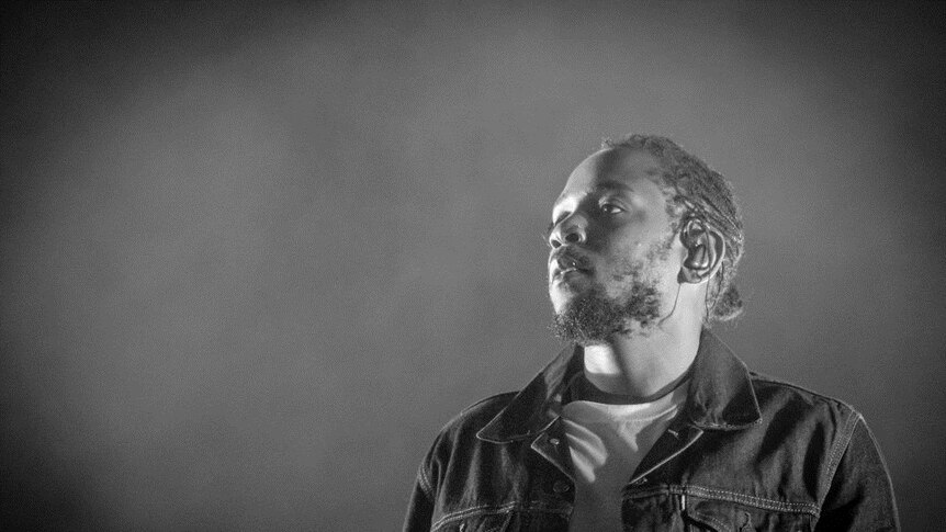 Black and white image of Kendrick Lamar performing on stage.