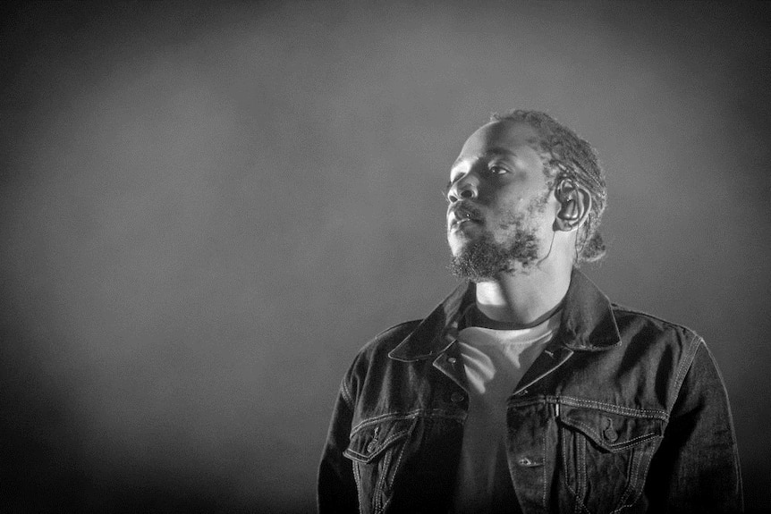 Black and white image of Kendrick Lamar performing on stage.