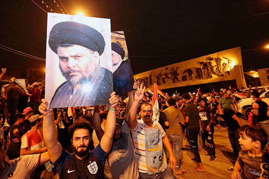 Men hold posters of Moqtada al-Sadr