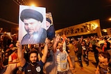 Men hold posters of Moqtada al-Sadr