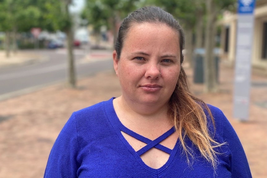 Brie wears a cobalt blue shirt and stands on a street in Port Lincoln looking directly at the camera.