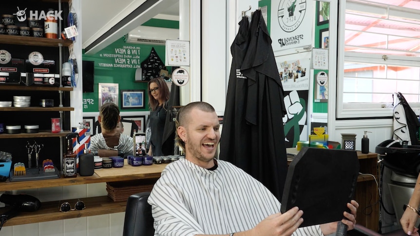 Stephen Stockwell admires his new haircut - the skullet - in the barber's mirror
