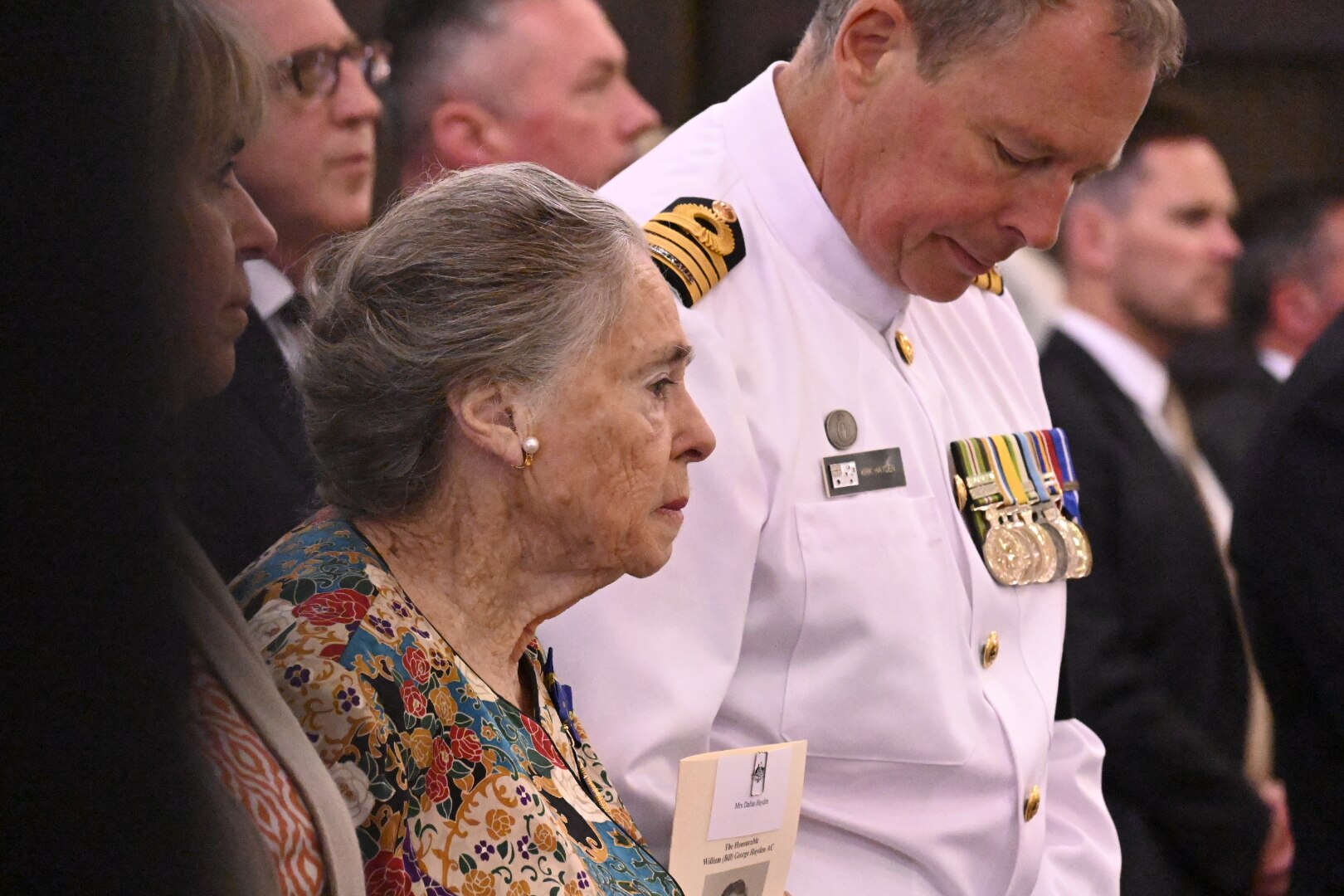 a woman standing in a pew in a packed church
