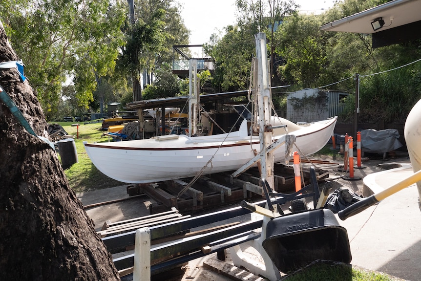 Une barque blanche se trouve au sommet de planches de bois au Carrington Boat Club à Brisabne