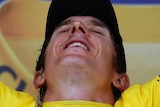 Geraint Thomas throws his head back with his eyes closed and arms aloft