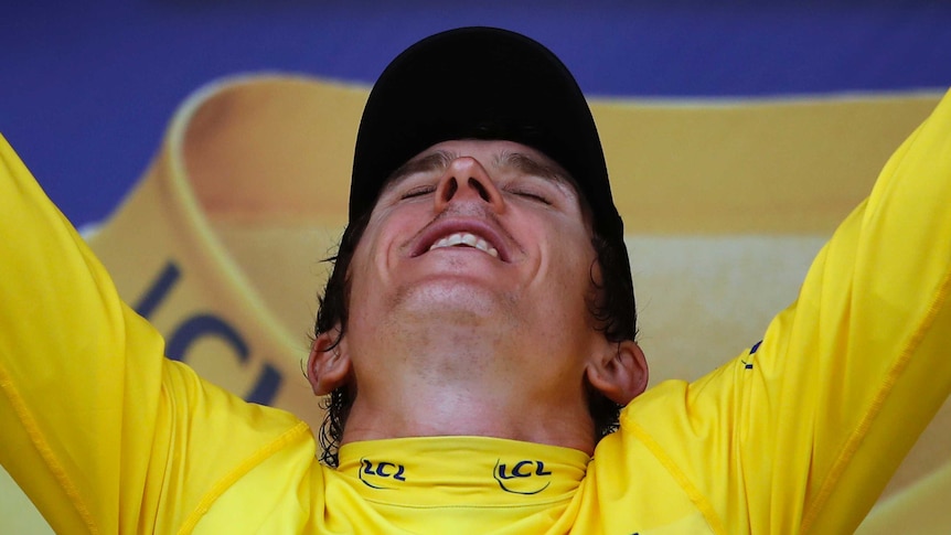 Geraint Thomas throws his head back with his eyes closed and arms aloft