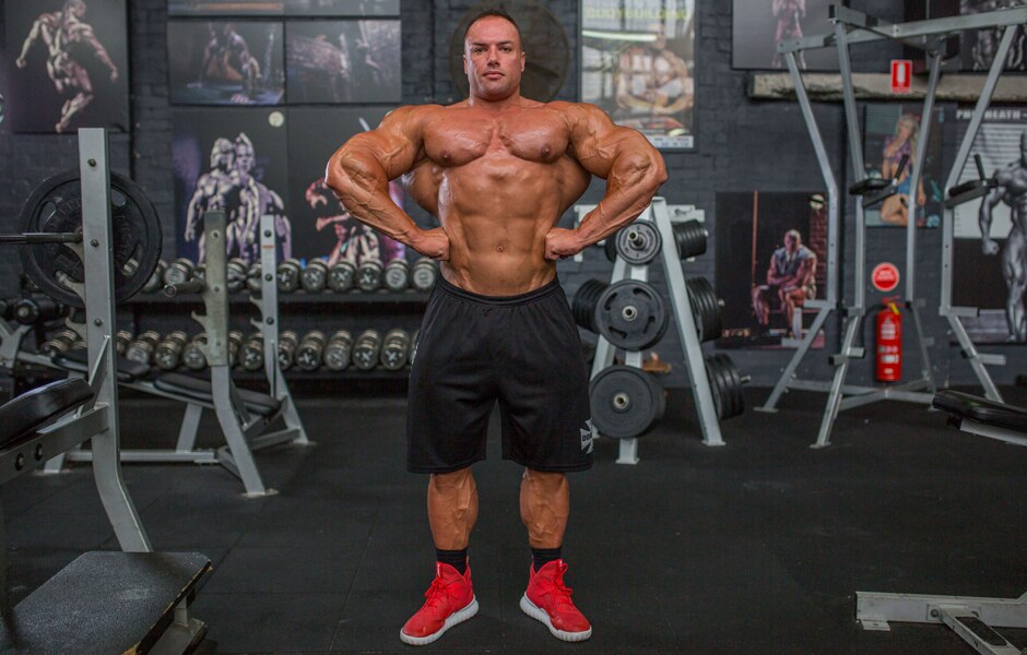 Bodybuilder Josh Lenartowicz wide shot in gym