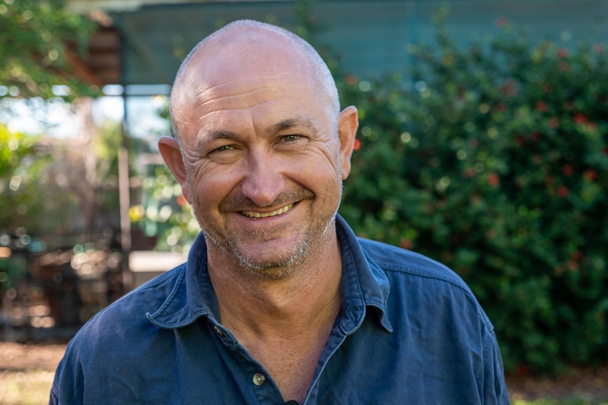 A balding man smiles widely at the camera.