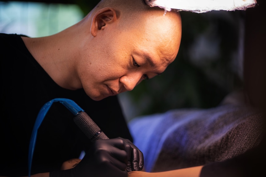 A bald Korean man in a tattoo parlour 