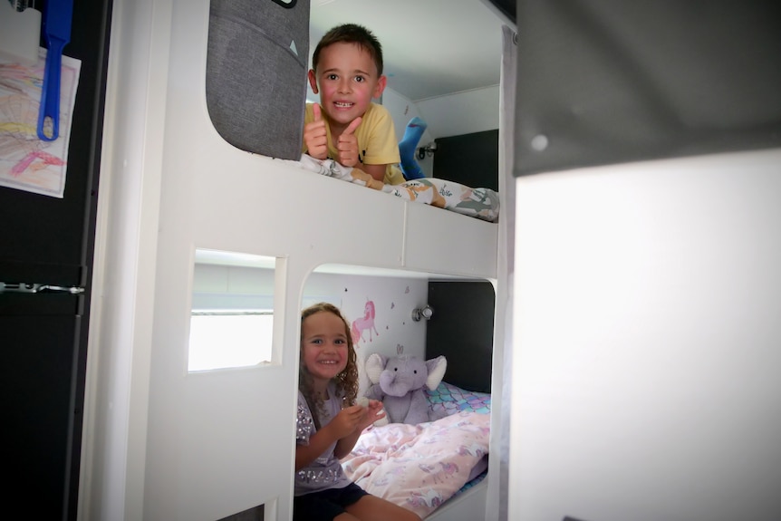 White bunk beds with a little boy and girl on top and bottom bunk respectively
