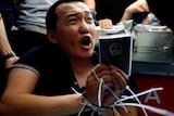 Chinese journalist Fu Guohao holding his passport with zip ties around his wrists