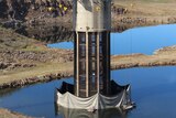 A tall tower-looking piece of infrastructure on a dam