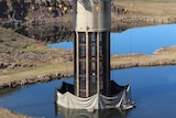 A tall tower-looking piece of infrastructure on a dam