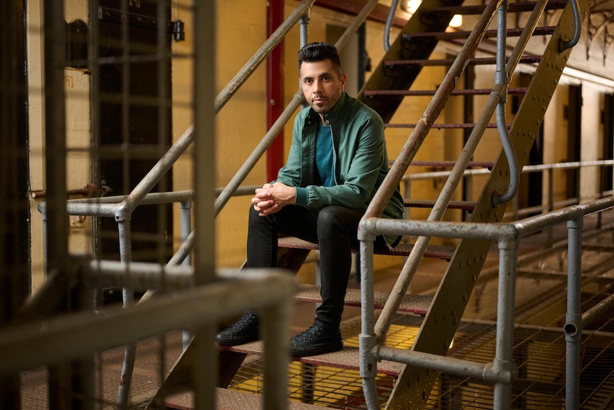 A man in a green shirt on jail steps.