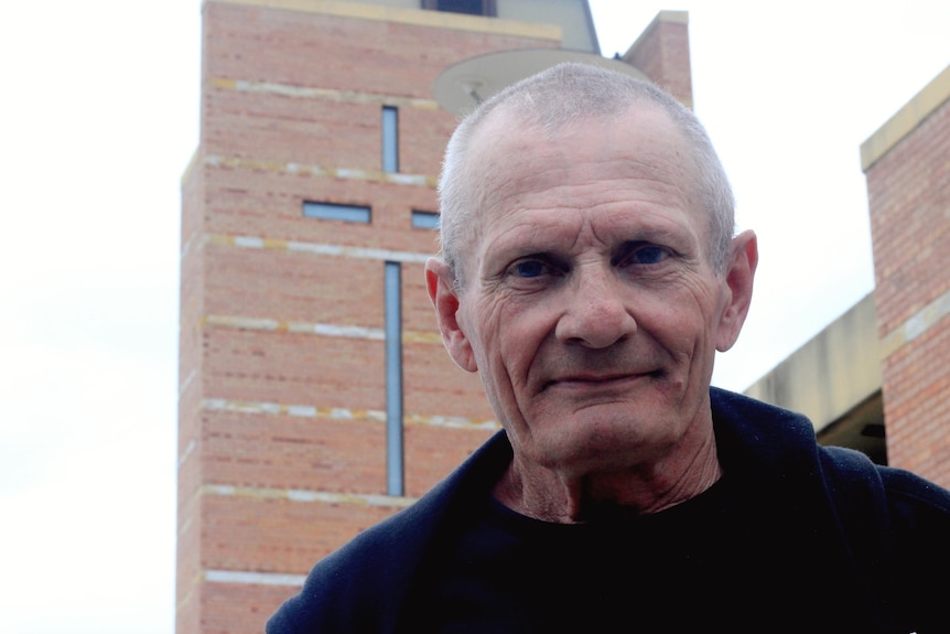 A man standing in front of a church with cross on it.