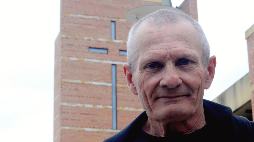 A man standing in front of a church with cross on it.