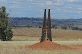 A giant peg in a paddock with other paddocks in the distance, in outback Australia.