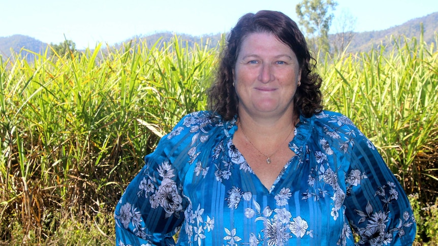 Woman standing in front of a sugarcane crop wearing a blue shirt