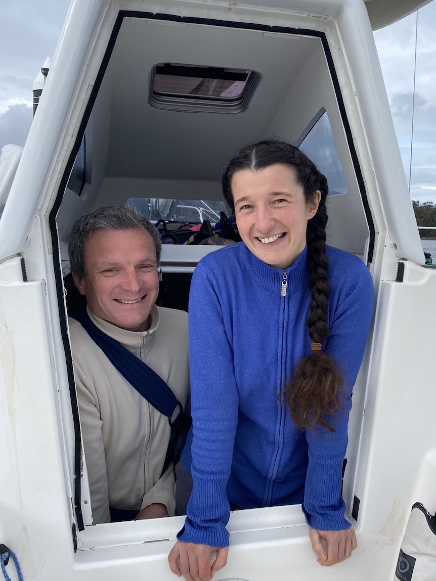 Sailors Carina Juhhova and Christophe Mora stand in the hatch of their yacht L'Envol.