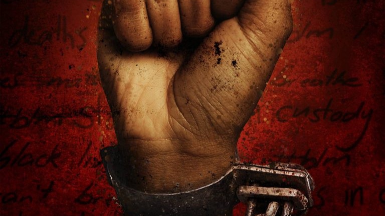 A dark-skinned fist raised in defiance of its wrist shackle. White block text above says "Incarceration Nation".