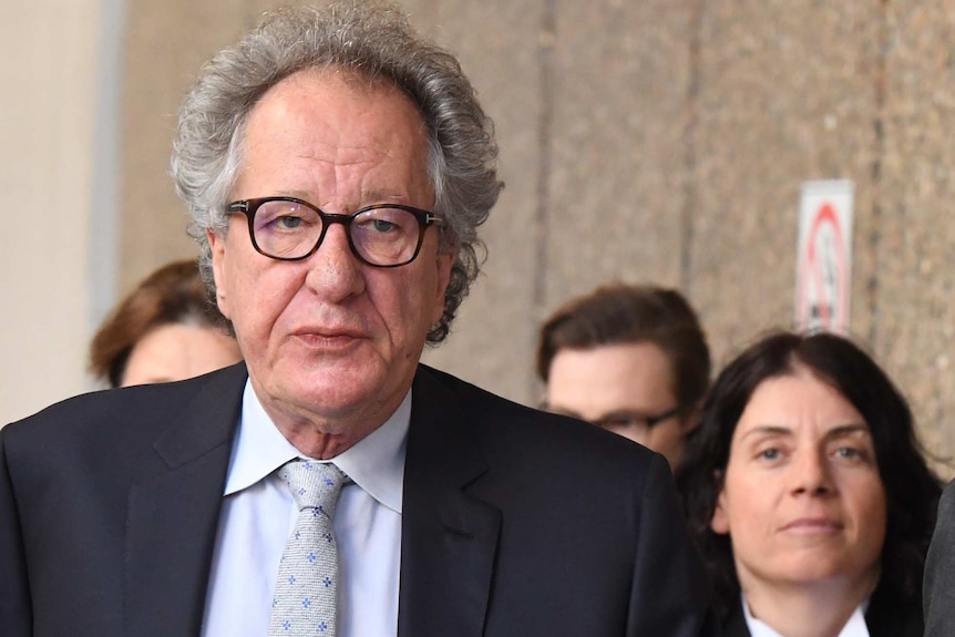 Geoffrey Rush arriving in court on Thursday, flanked by some of his legal team