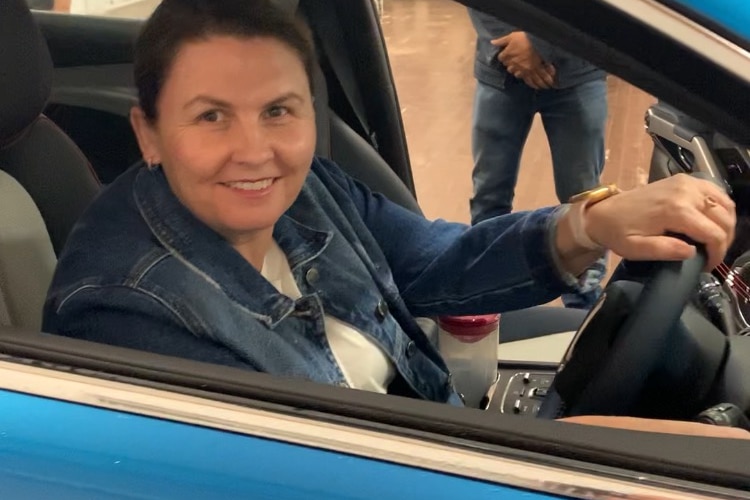 Femme assise dans une nouvelle voiture bleue dans une salle d'exposition en souriant