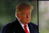 Donald Trump holds an umbrella in the rain