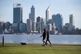 A man and a woman wearing masks walk a dog along South Perth foreshore.