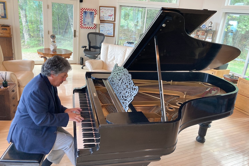 Friedman, con una chaqueta de tweed azul, se sienta a tocar el piano de cola Steinway en un solárium lleno de luz