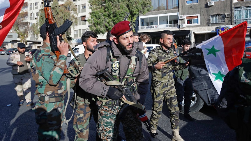 Syrian soldiers wave weapons and national flags as they chant slogans against US President Donald Trump/