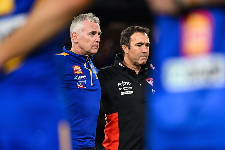 West Coast Eagles and Essendon Bombers coaches Adam Simpson and Brad Scott stand arm in arm before an AFL game.
