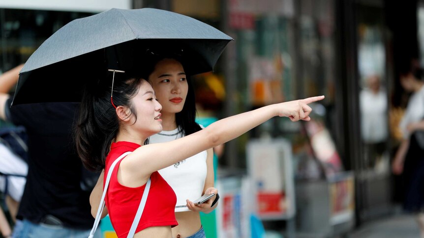 Women use a parasol at a shopping district in Tokyo.