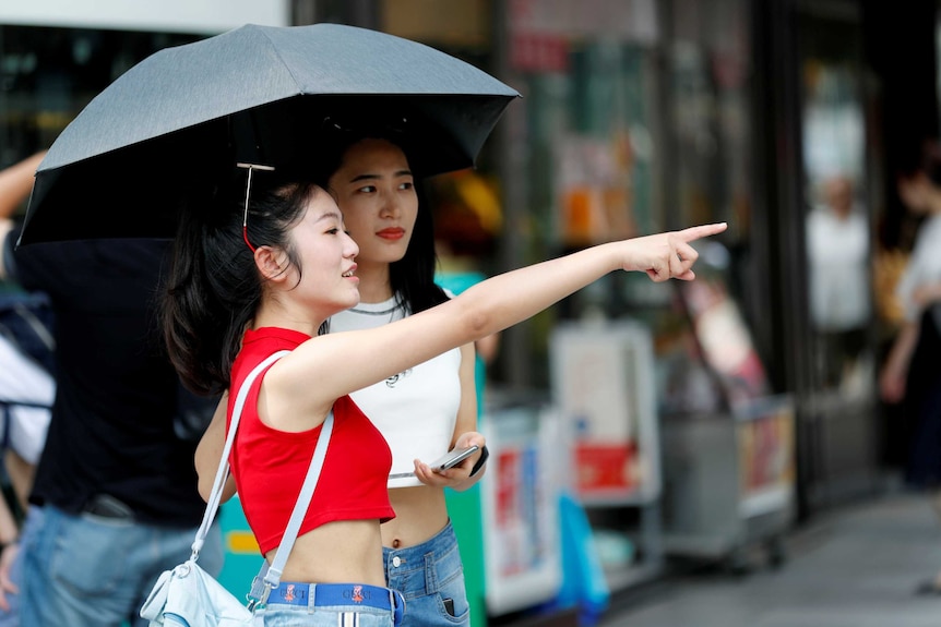 Women use a parasol at a shopping district in Tokyo.
