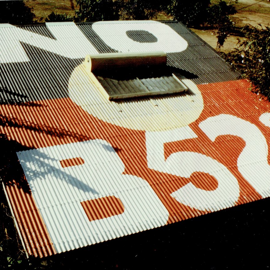 The roof of a house is painted with the aboriginal flag and the words no b fifty twos