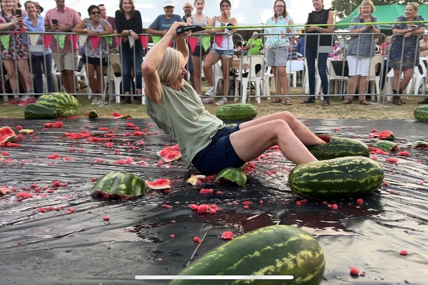 A woman skis across a tarp with her feet in watermelons.