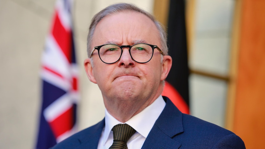 Anthony Albanese frowns while speaking at a press conference outside his office