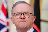 Anthony Albanese frowns while speaking at a press conference outside his office