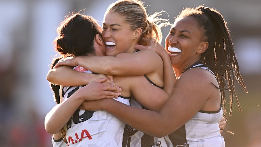 Collingwood players hug in celebration of a goal