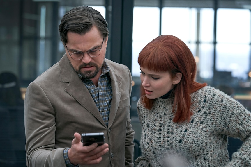 Leonardo DiCaprio and Jennifer Lawrence look at a phone in shock in an image from the film.