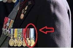 Close up of a man wearing a row of war medals, with a red circle drawn around one and a red arrow pointing to it